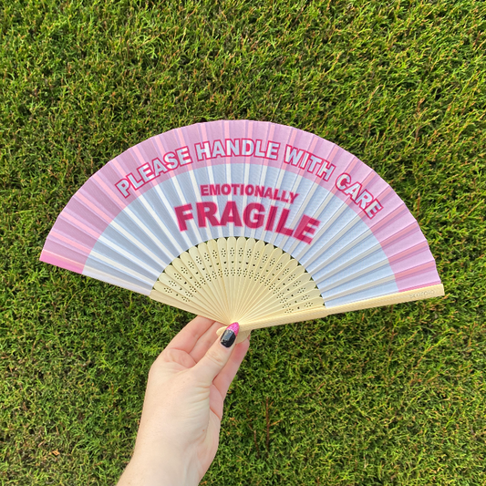 Handheld Fan with pink and white lettering reading "Please handle with care, Emotionally Fragile" with natural Bamboo Spines