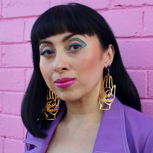 18K Gold Statement Earrings shaped as a hand and reading "Bitch Please" featuring Lapis Lazuli rough cut crystals modelled by Margeaux in front of a pink brick wall