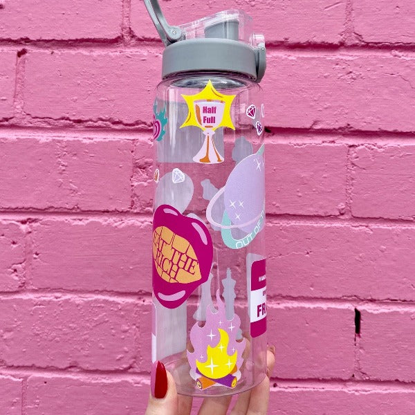 Two bold coloured fun sticker on a water bottle held up in front of a pink brick wall. Featuring stickers such as Eat the Rich, Just like Magic, You are Art.