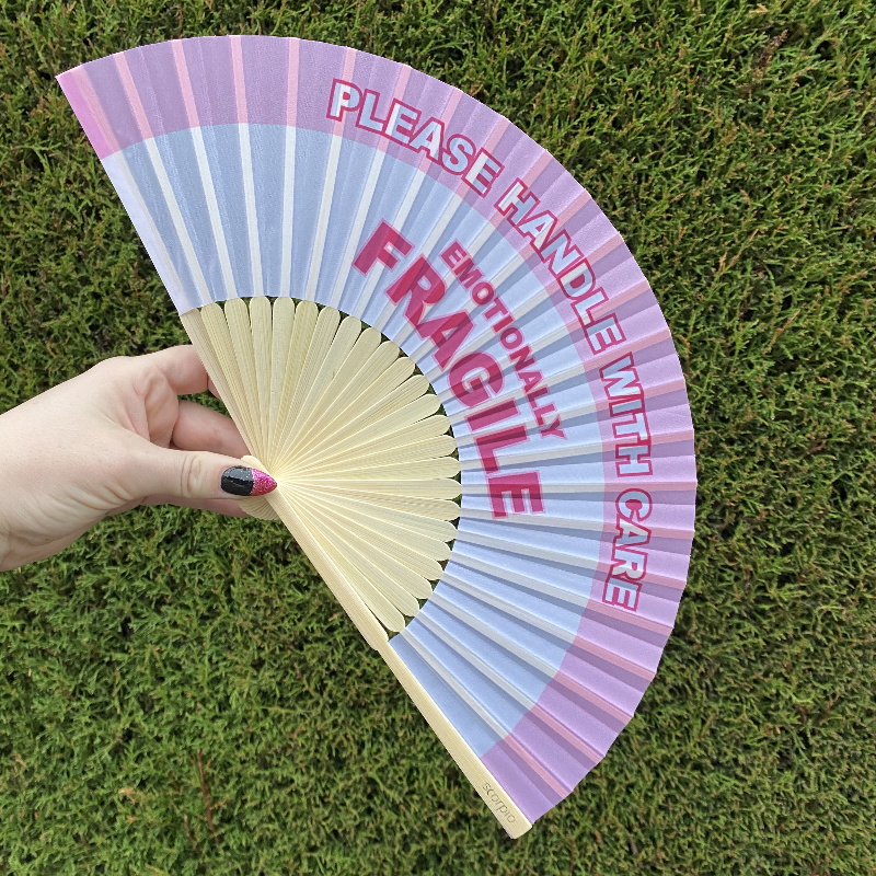 Handheld Fan with pink and white lettering reading "Please handle with care, Emotionally Fragile" with natural Bamboo Spines