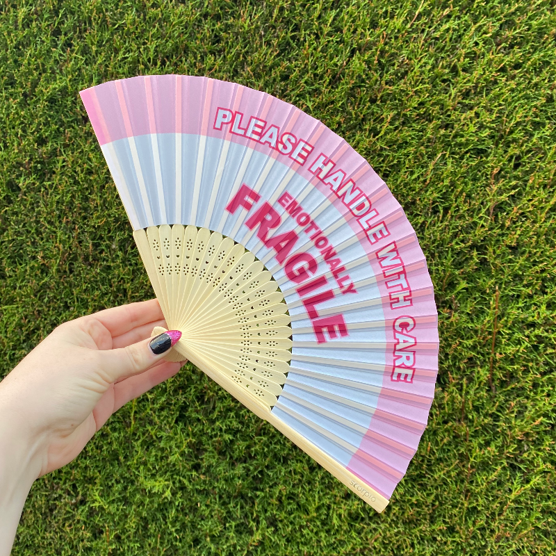 Handheld Fan with pink and white lettering reading "Please handle with care, Emotionally Fragile" with natural Bamboo Spines