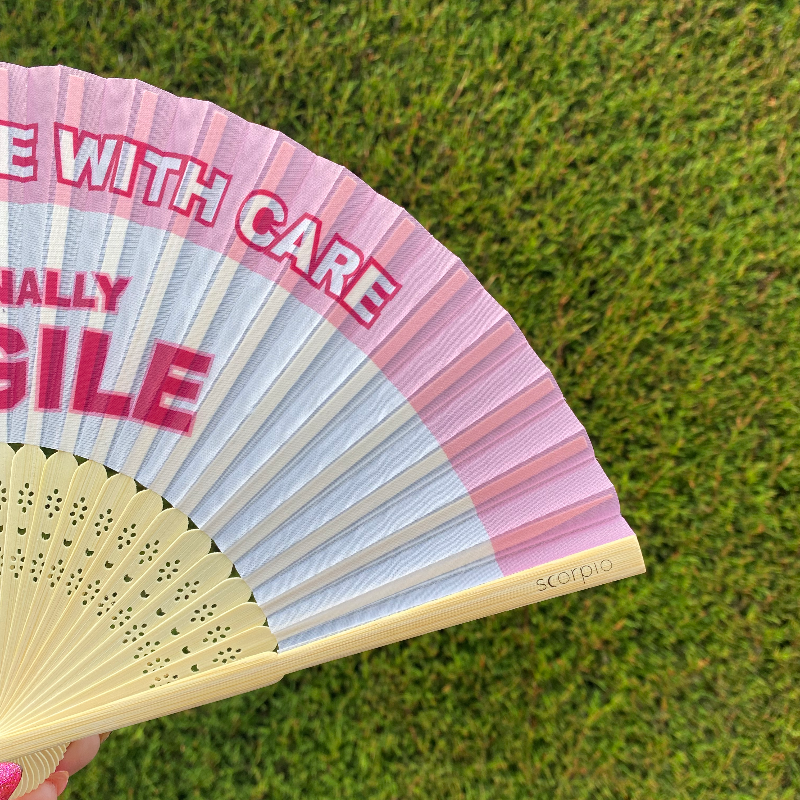 Handheld Fan with pink and white lettering reading "Please handle with care, Emotionally Fragile" with natural Bamboo Spines